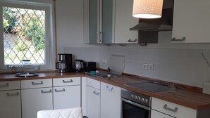 Cocina moderna con armarios blancos, encimera de madera y dos lámparas colgantes.
