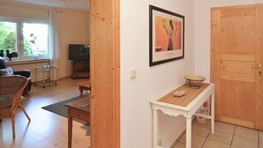 Een woonkamer met een televisie, een bank, een salontafel en een deur.