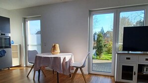 Een moderne woonkamer met een eettafel, een televisie en uitzicht op de omgeving.
