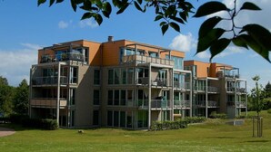 Een modern meerlaags appartementencomplex met balkons, grote ramen en een verzorgd gazon.