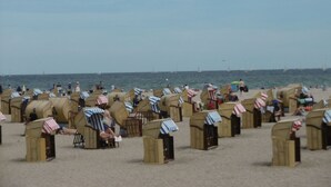 Een strand met talloze houten hutten voorzien van gestreepte luifels, waarvan enkele de Amerikaanse vlag hebben.