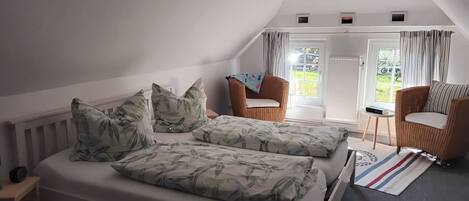 Ein Schlafzimmer mit Schlafkoje, zwei Stühlen, einem kleinen Tisch und Blick ins Freie.