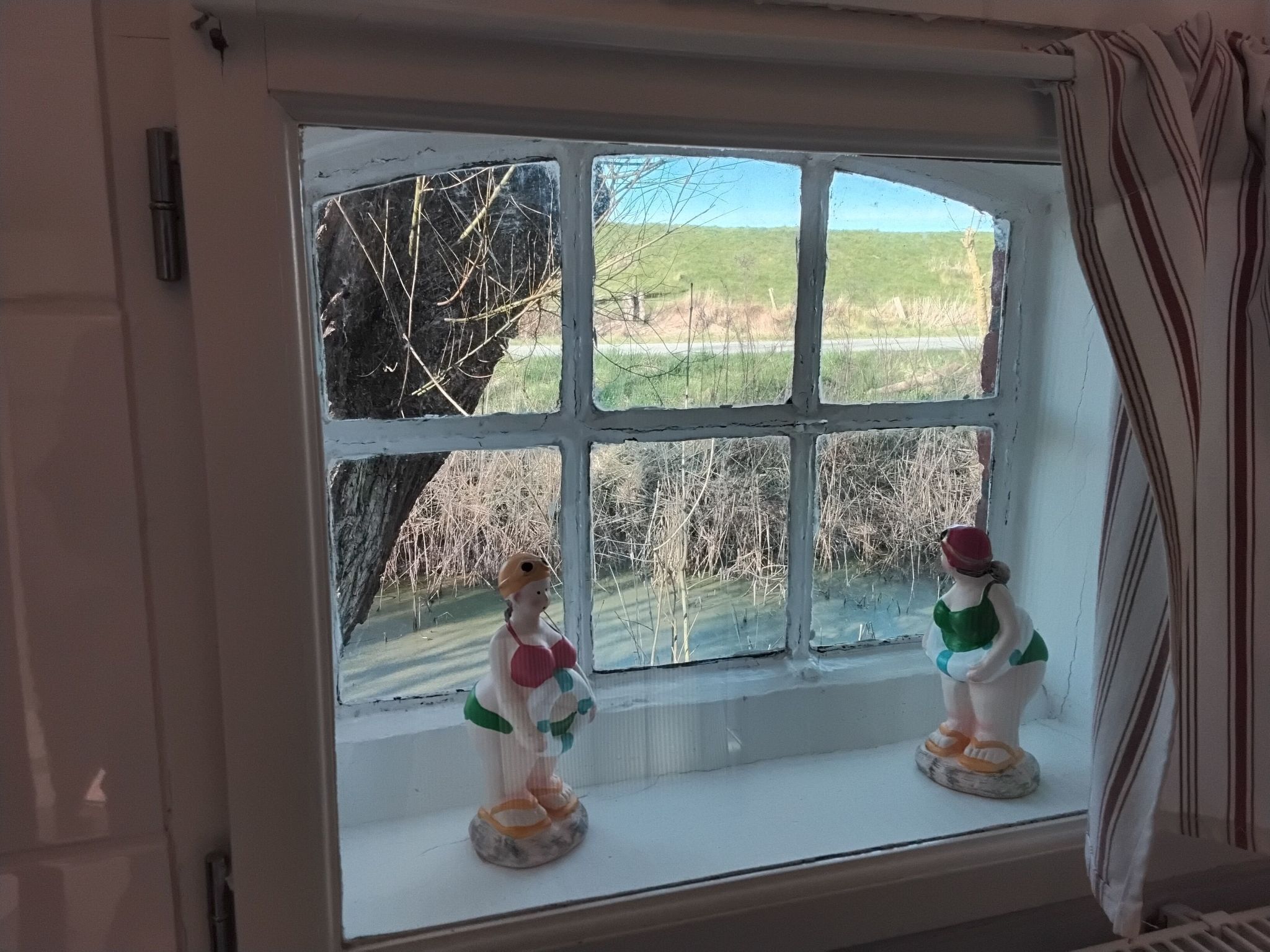 A window with two ceramic figurines on the sill.