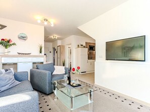 Een moderne woonkamer met een bank, salontafel en een keuken op de achtergrond.