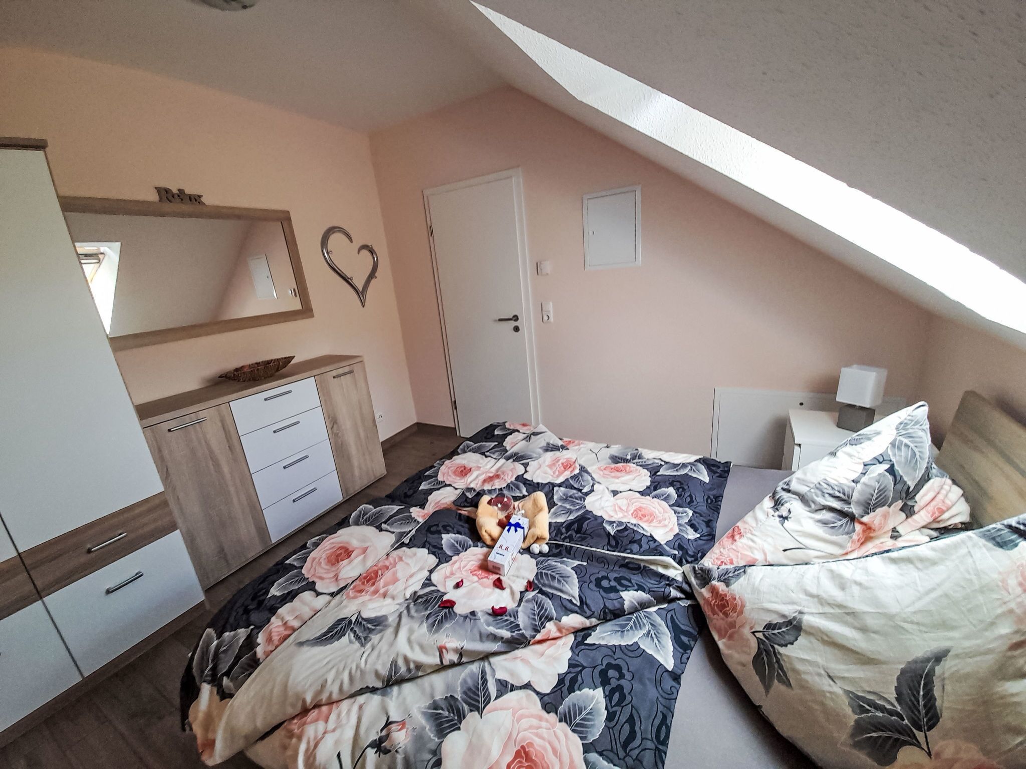 Een slaapkamer met een bed, een dressoir en een deur.