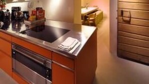 Een moderne keuken met een centraal eiland, een inbouwoven en houten balkenplafond.