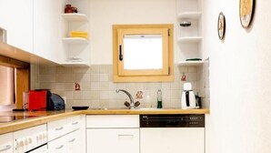 A modern kitchen with white cabinetry, a wooden countertop, a built-in oven, and a dishwasher. - Chesa La Capriola by Interhome (Sils Maria)