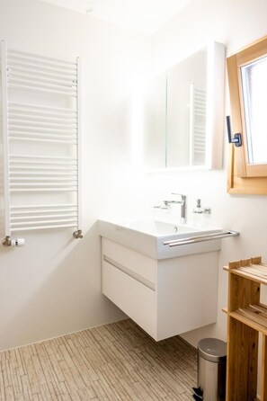 A modern bathroom with a white vanity, a mirror, and a window with blinds. - Chesa La Capriola by Interhome (Sils Maria)