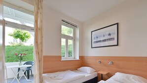 A hotel room with two beds, a window, a framed picture, and a view of greenery outside. - Villa Celia Sellin by Interhome (Ostseebad Sellin)