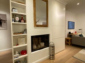 A modern living room with a fireplace, shelves with various items, a mirror, and a television. - Engiadina Libra by Interhome (Celerina)