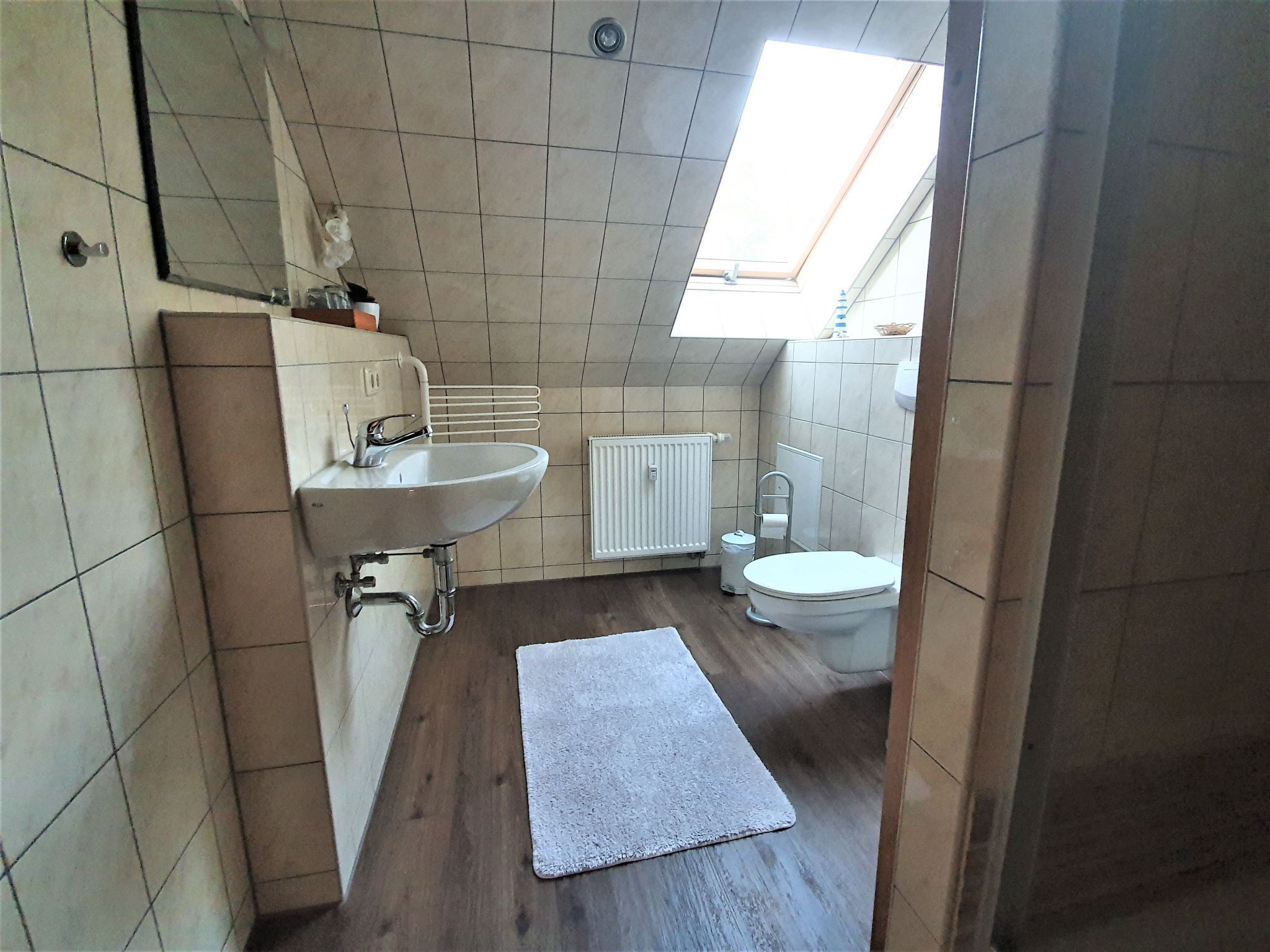 A small bathroom with a sink, toilet, and a window.