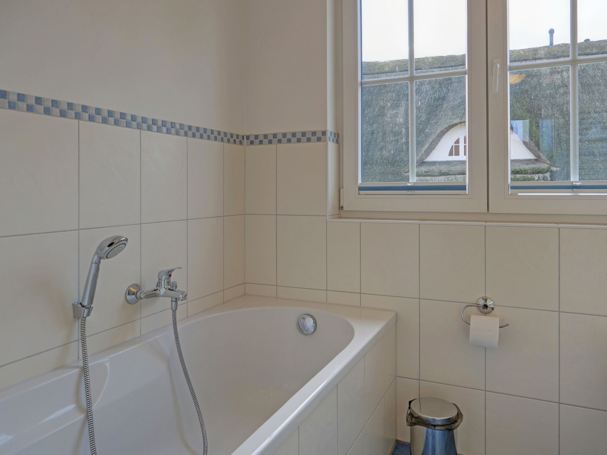 Ein Badezimmer mit Badewanne, einem Fenster mit Blick auf Häuser und einer Toilette.