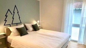 Quarto com cama, mesas de cabeceira e janela com cortinas.