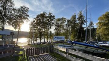 Ein Yachthafen am See mit vertäuten Booten, einer Holzlattenzäunung und einem Schild mit der Aufschrift 'Segelverein'.