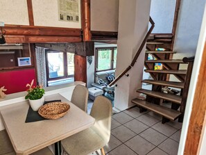 A dining area with a table, chairs, a basket, and a potted plant.