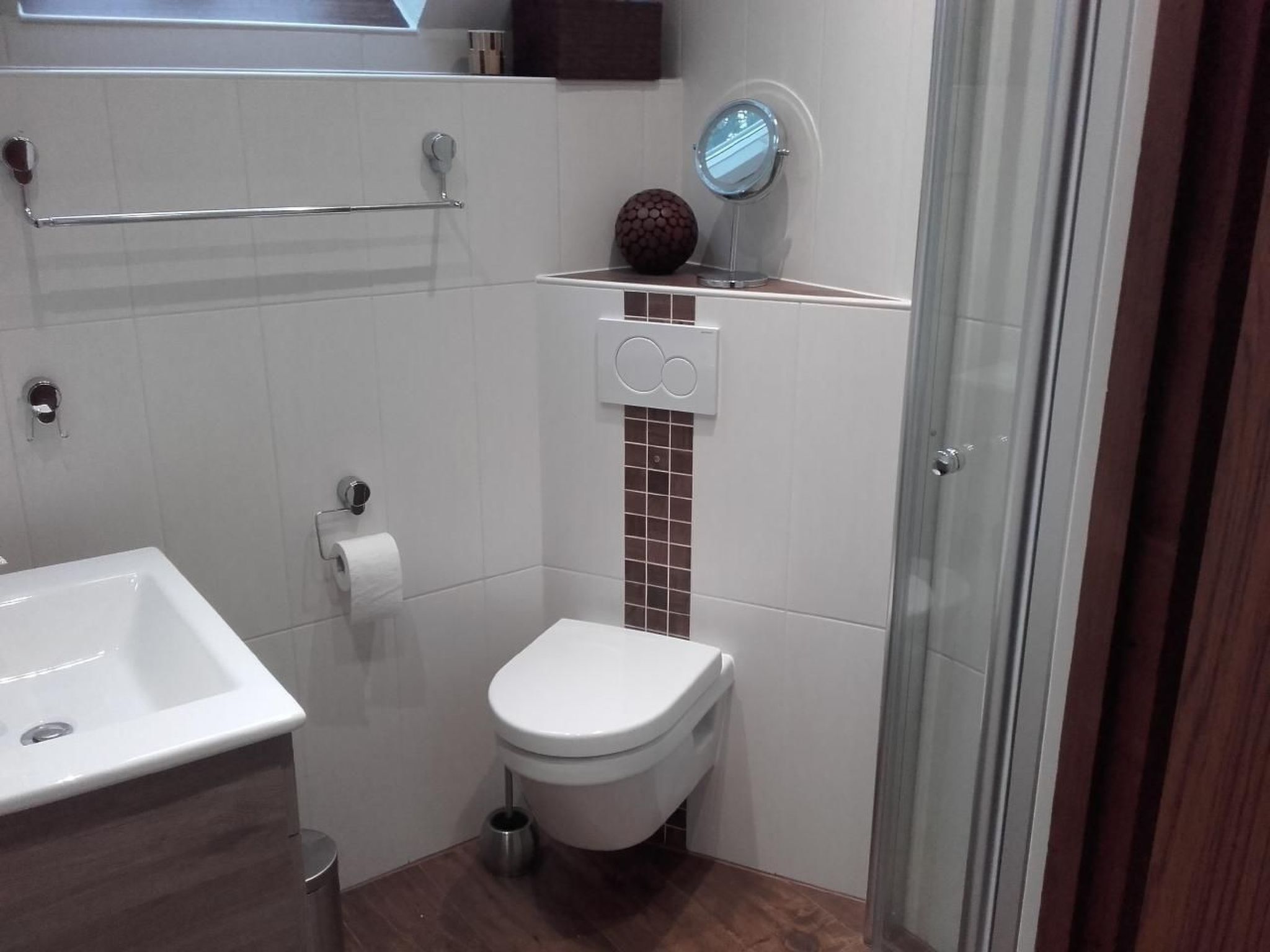 A modern bathroom with a white sink, toilet, and shower area.