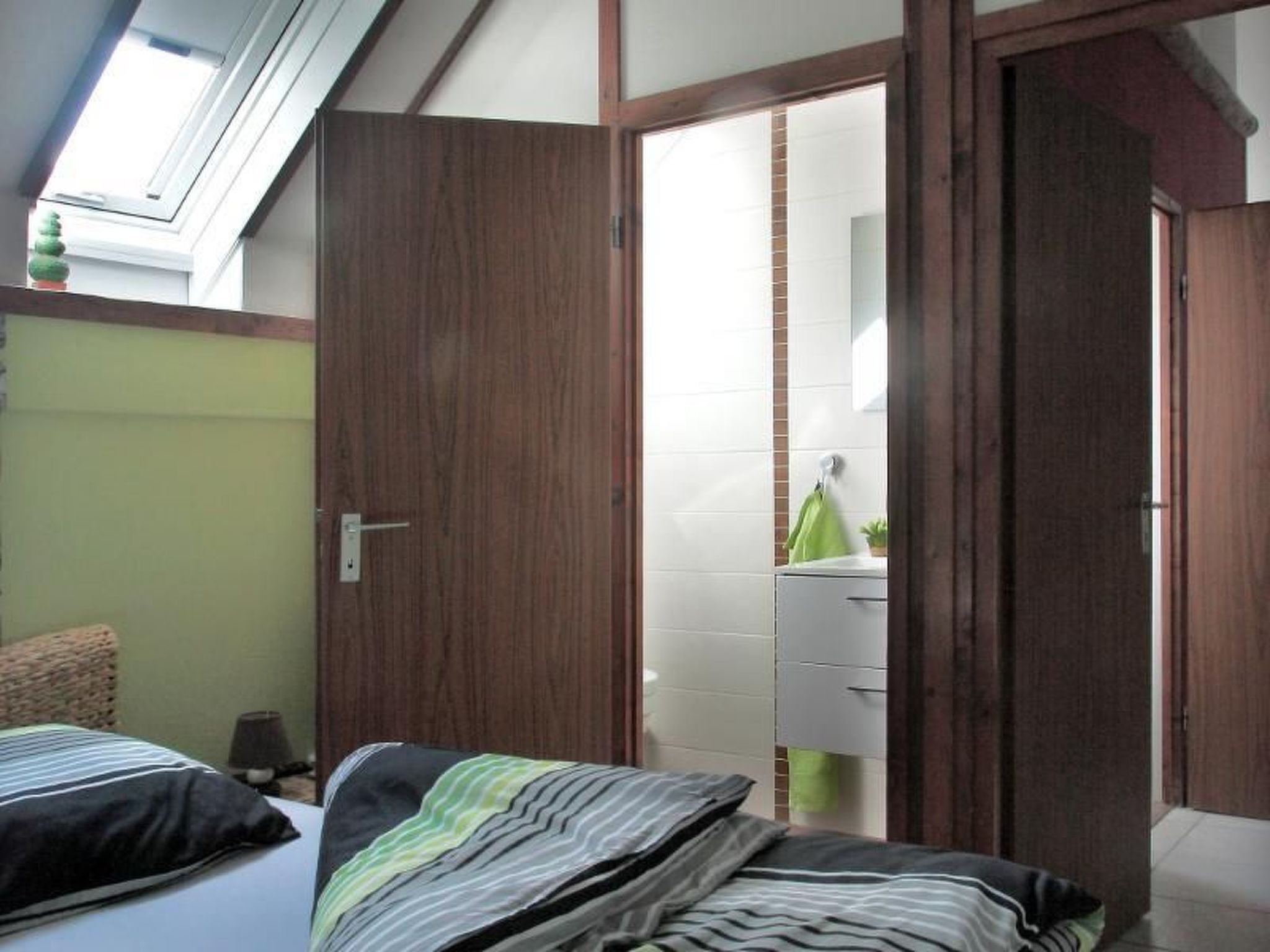 Ein Schlafzimmer mit Bett, Fenster und einer Tür zu einem Badezimmer.
