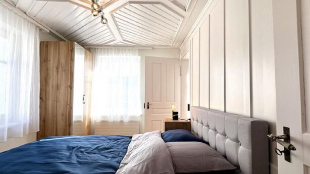 A bedroom with a large bed, a wooden door, and a ceiling with a geometric design. - Rhänstrasse 9 in Gais AR by Interhome (Gais)
