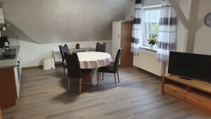 Un espace de vie compact comprenant un coin repas, une kitchenette et un téléviseur.