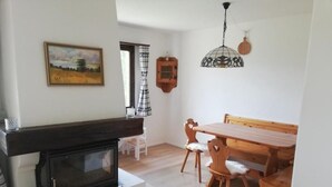 A cozy living room with a fireplace, wooden dining table, and chairs.