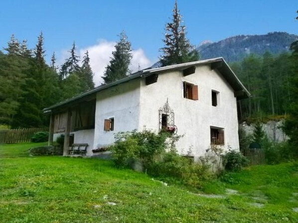 A white building with a sloped roof, surrounded by greenery and trees.