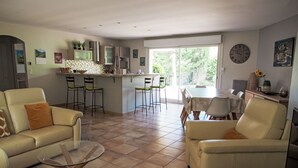 Un ampio soggiorno con angolo cottura e zona pranzo. Ci sono due divani e un tavolino da caffè. La cucina è dotata di elettrodomestici moderni e di una grande finestra.