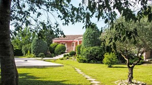 Un giardino curato con un vialetto lastricato che conduce a un edificio con tetto rosso.