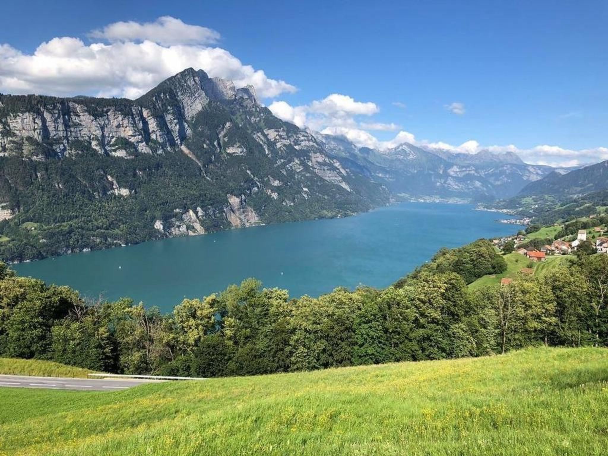 Un paysage montagneux avec un lac et un village situé dans la vallée.