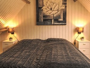 A bedroom with a bed, two bedside tables, a wall-mounted lamp, and a large abstract painting. - Sommerhaus "De Zeester" by Interhome (Egmond aan Zee)