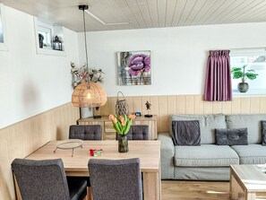 A modern living room with a dining area, a sofa, a table with chairs, a hanging light fixture, and a window with curtains. - Sommerhaus in ruhiger Lage mit privatem Garten und Terrasse by Interhome (Egmond aan Zee)