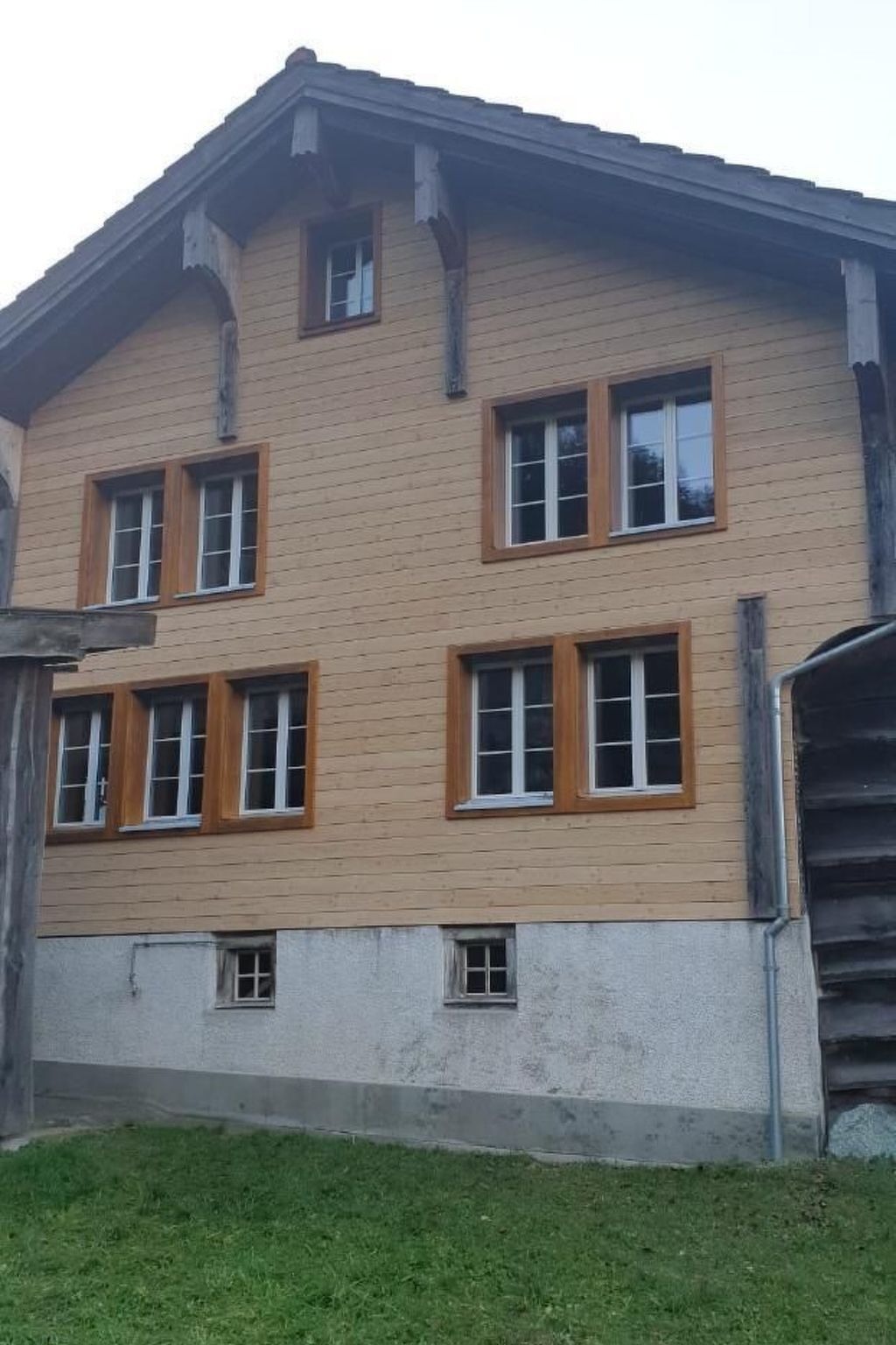 A multi-story building with a beige exterior and multiple windows with wooden frames.