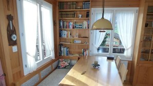 Ein gemütliches Zimmer mit Holztisch, Bücherregalen und einer Bank.