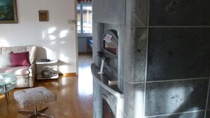 Ein Wohnzimmer mit Kamin aus Stein, einem Glastisch, einer Couch und einem Teppich.
