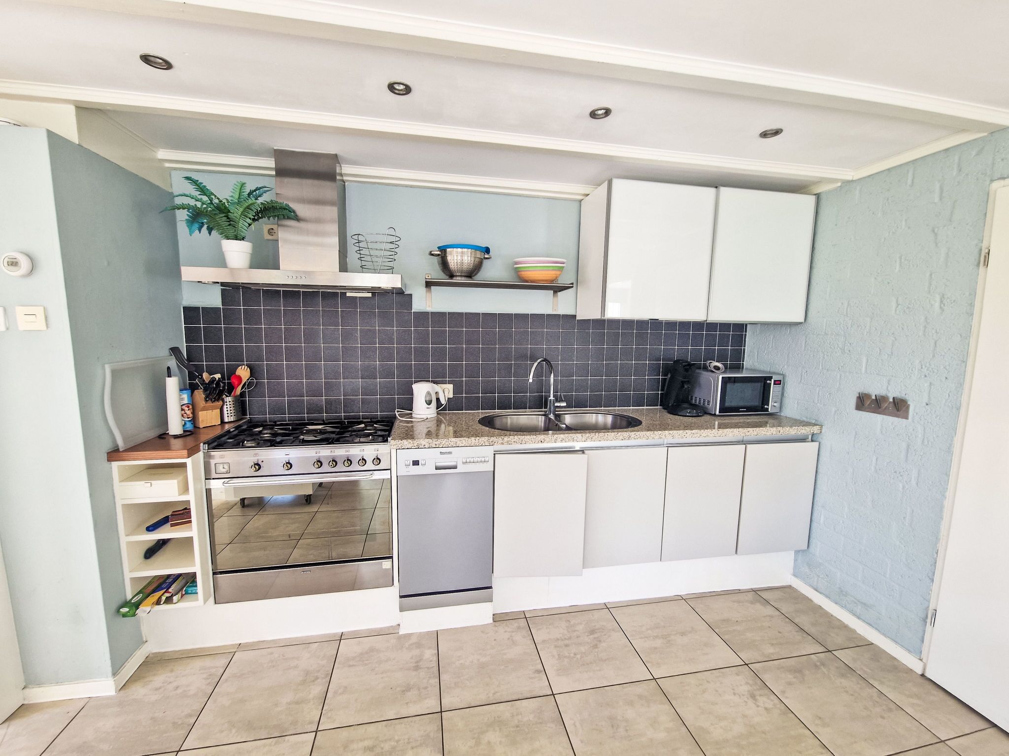 A compact kitchen with a gas stove, oven, dishwasher, and a microwave.