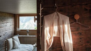 Una habitación acogedora con piso de madera, un sofá blanco y una ventana con vistas a un paisaje montañoso.