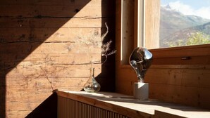 Un interior de madera con una ventana, un radiador y una escultura en el alféizar.