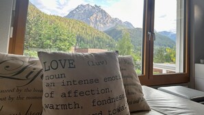 A bedroom with a large window offering a mountain view. There are two pillows with printed text on them. - Chasa Stefania by Interhome (Scuol)