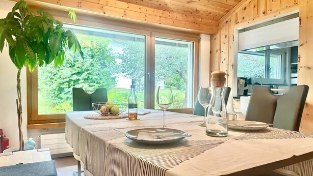 A dining area with a table set for two, a plant, and a view of the outdoors. - Chasa Stefania by Interhome (Scuol)