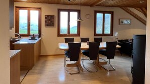 Ein Essbereich mit Holzboden, großen Fenstern und Blick auf die Landschaft.