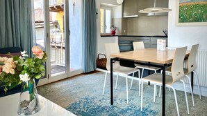 Ein moderner Essbereich mit Tisch und Stühlen, einer Blumenvase und Blick ins Freie durch eine Schiebetür.