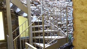 Eine Wendeltreppe mit Metallgeländern, umgeben von Steinmauern und einer gelben Wand.