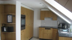 Une cuisine compacte avec des meubles en bois, un four encastré et un lave-vaisselle.