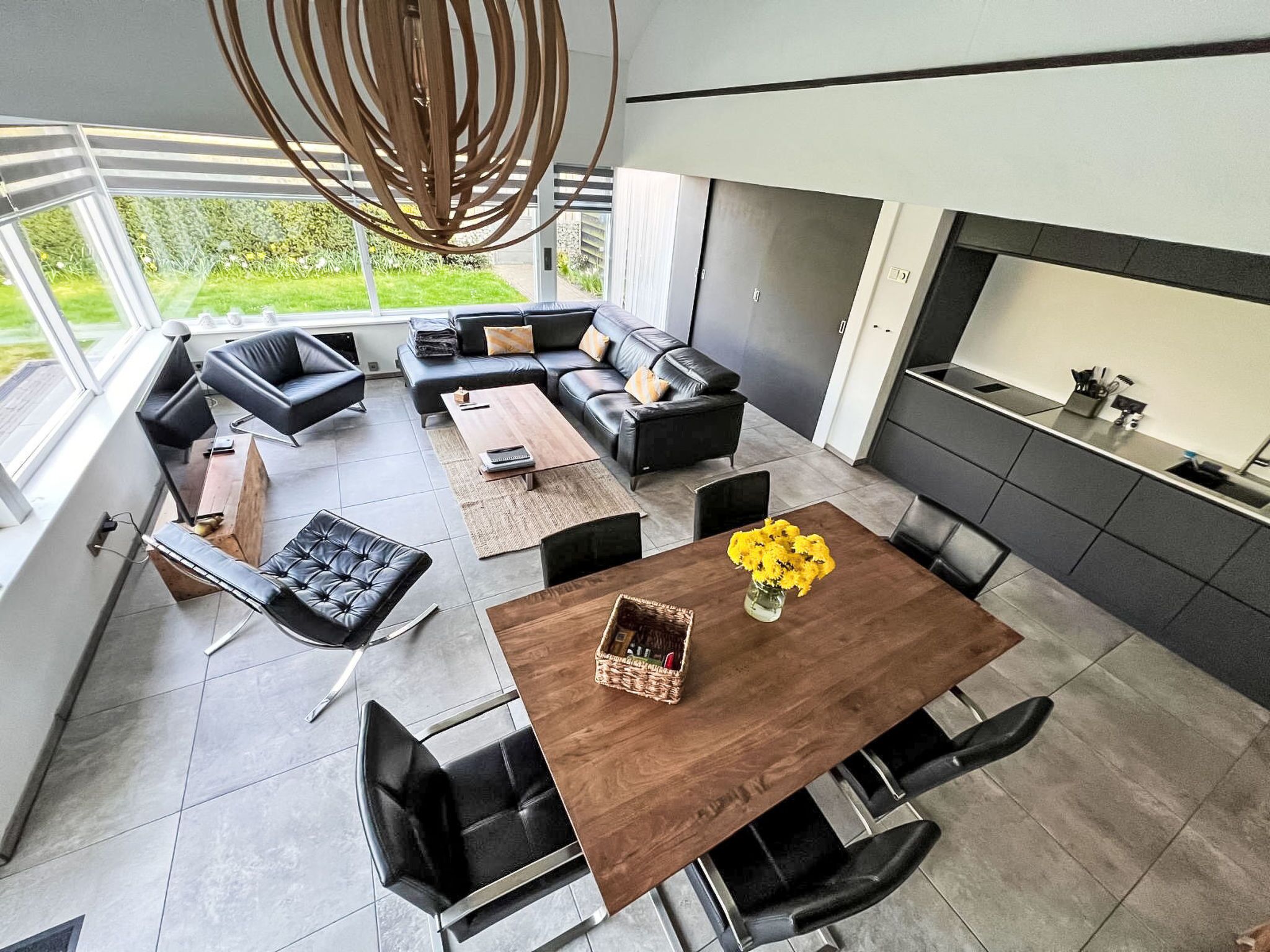 Een moderne, open woonkamer met een eettafel, banken en een keuken.