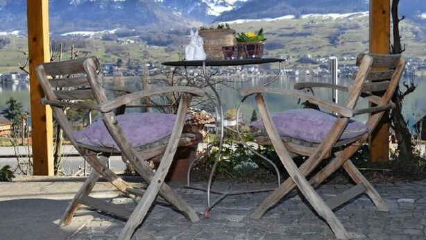 A wooden table with two chairs, a small table, and a vase with flowers. - Seeblick by Interhome (Sarnen)