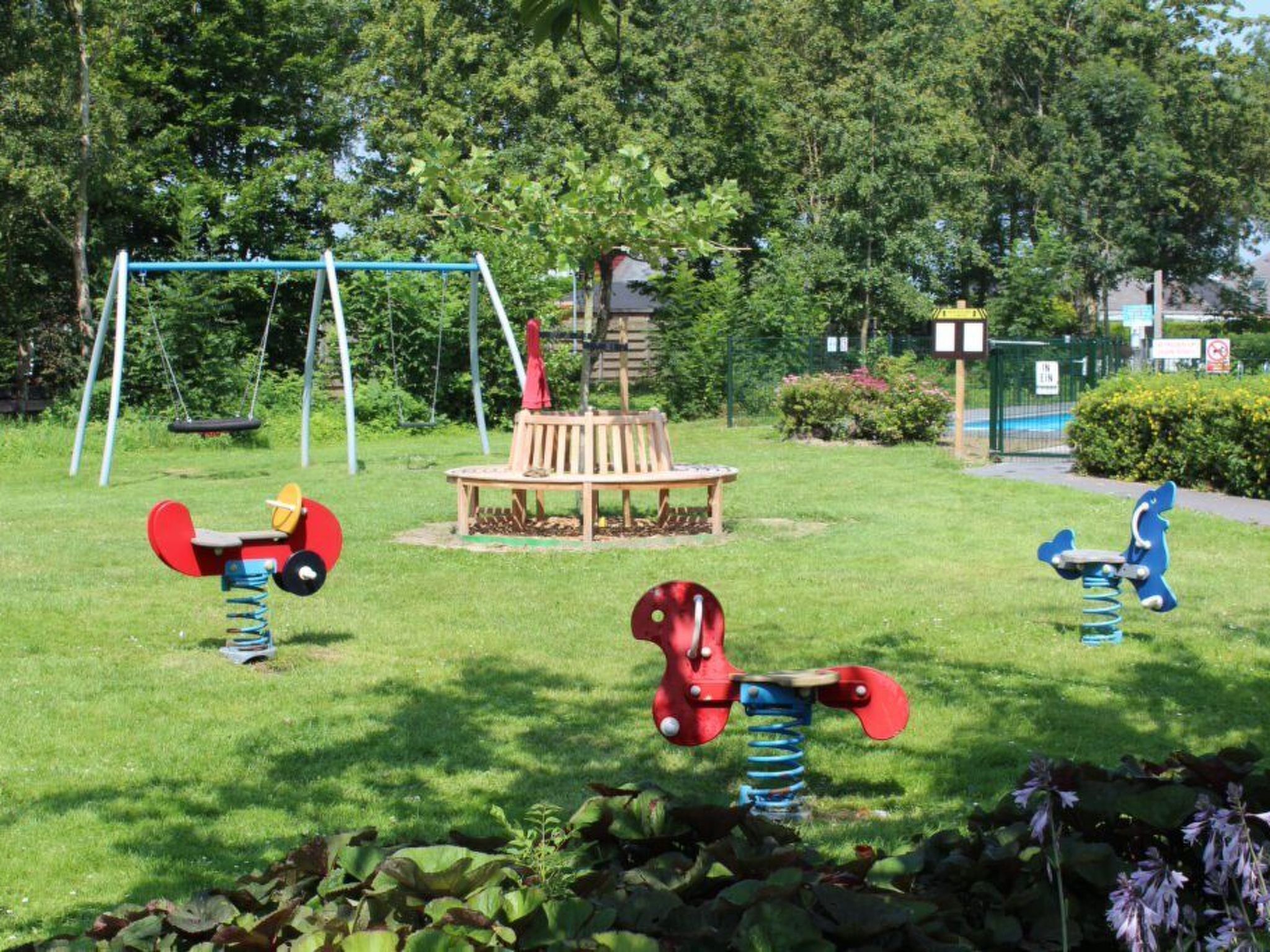 Een speeltuin met schommels, een glijbaan en een klimconstructie.