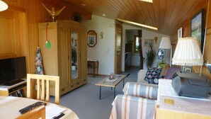 Una sala de estar acogedora con muebles de madera, un televisor y un comedor con una mesa y sillas.
