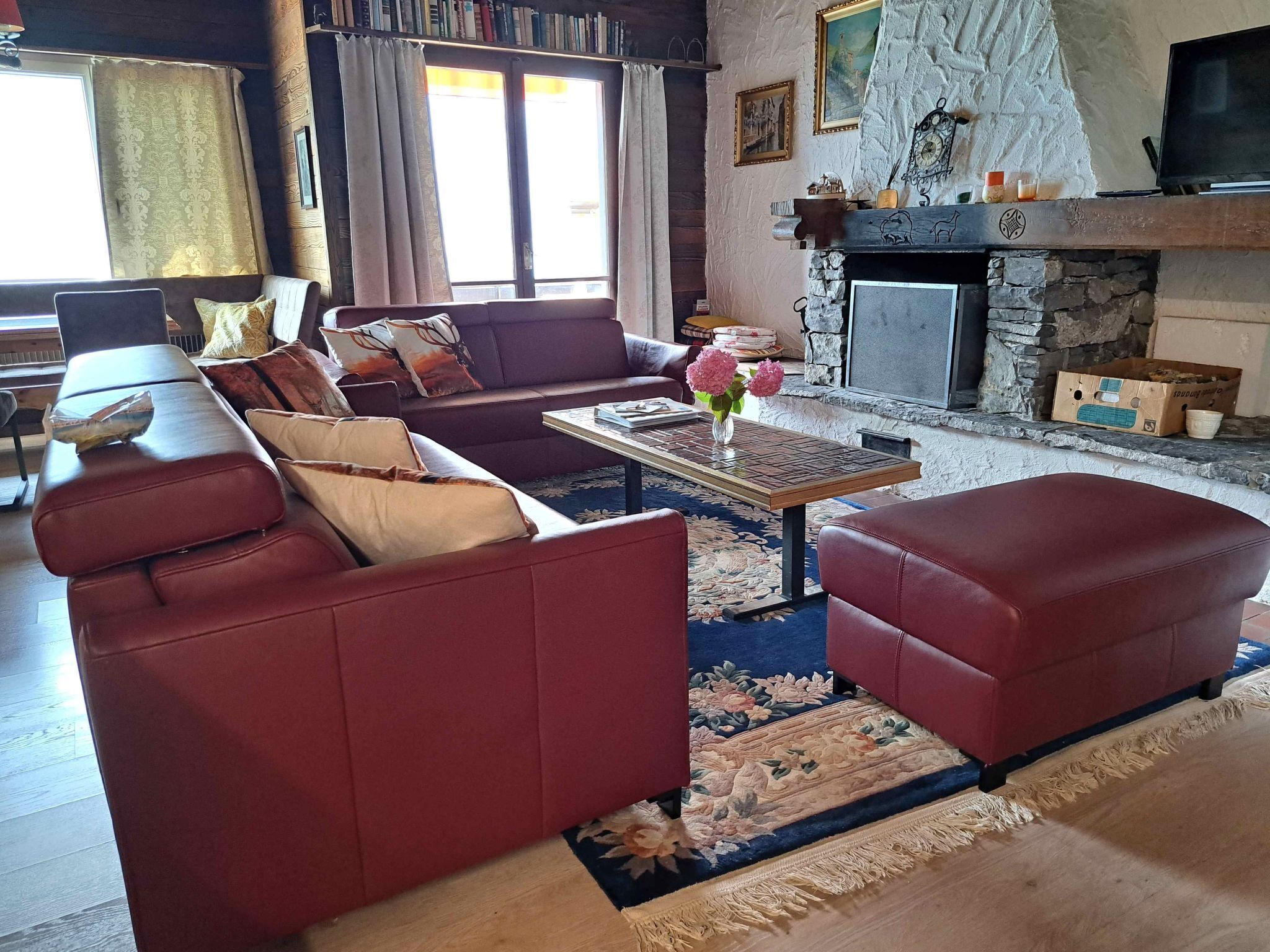 A cozy living room with a fireplace, a sofa set, a coffee table, and a bookshelf.