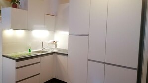 Una cocina pequeña con gabinetes blancos, un lavamanos y una encimera.