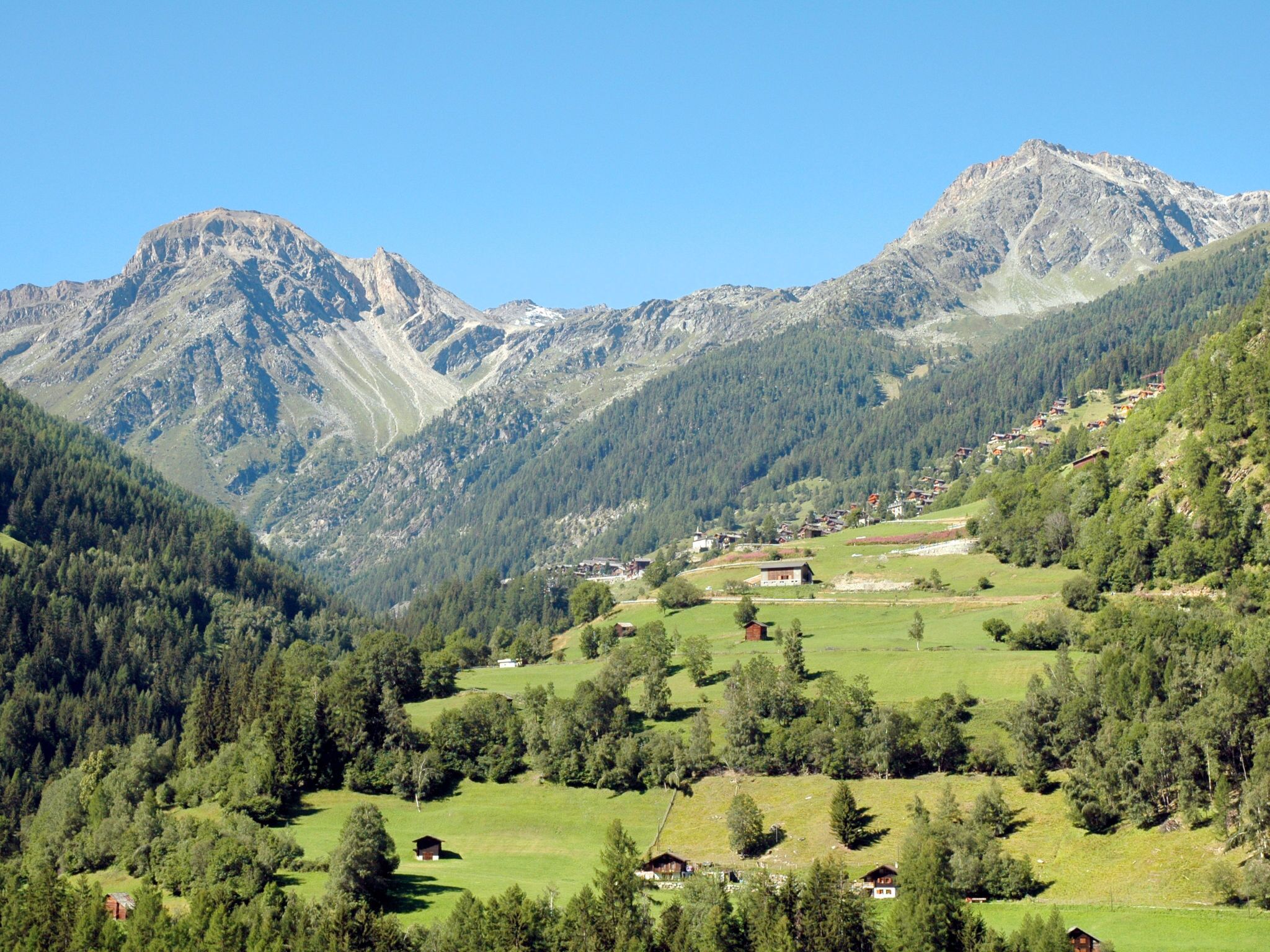 Un paysage montagneux parsemé de maisons, sous un ciel dégagé.