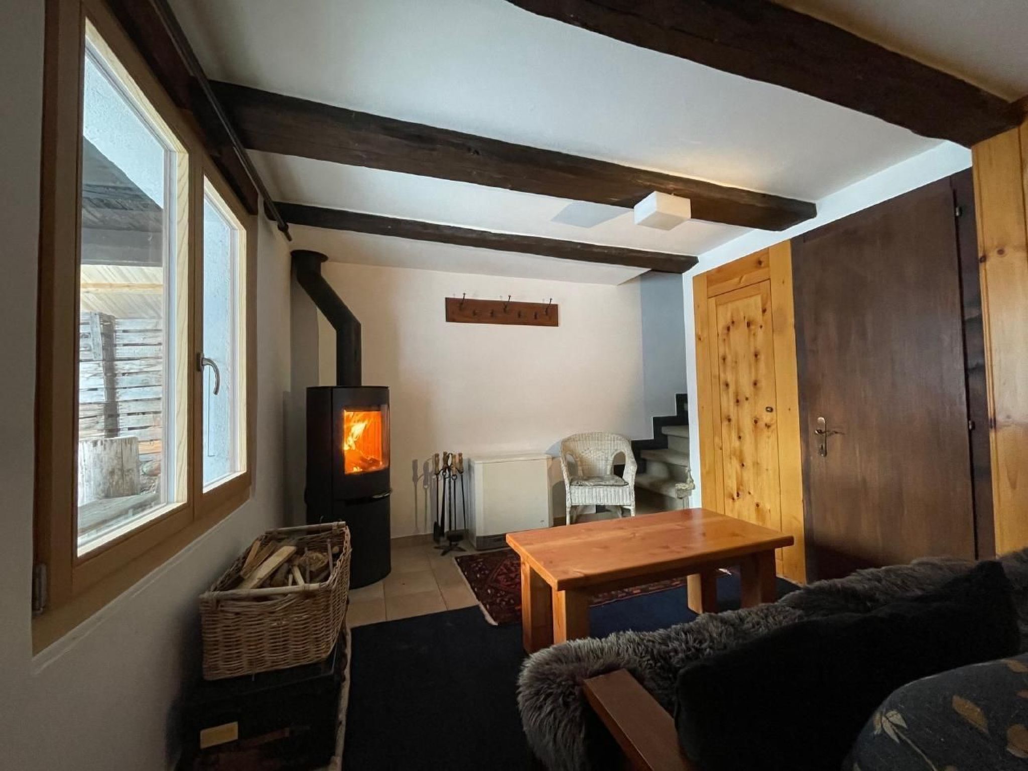 Ein gemütliches Wohnzimmer mit Kamin, einem Korbwäschekorb, einem Holztisch und einer Couch.